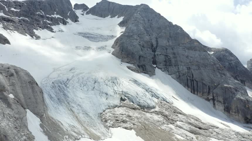 Snow and glacier covers mountainous terrain on a cloudy day