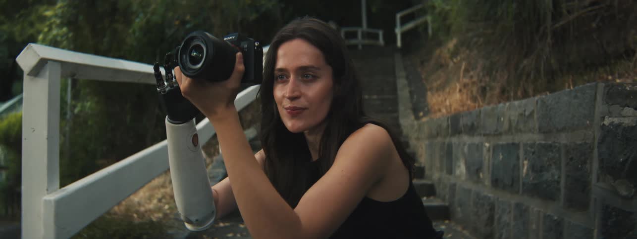 Young woman crouching and taking photos with her professional camera outdoors