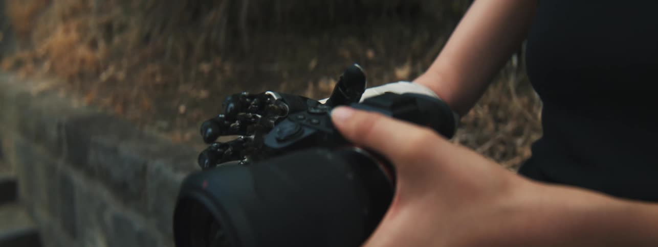 A woman testing her mechanical prosthetic hand by holding a camera