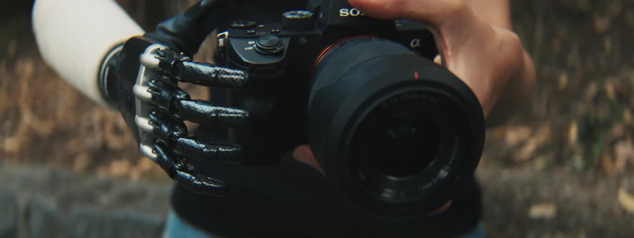 A person with a prosthetic hand holds a professional camera