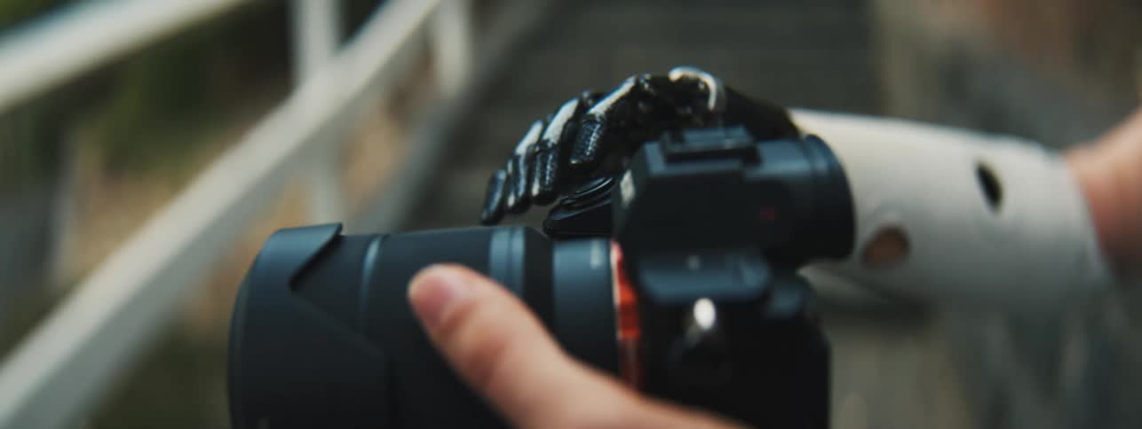 A prosthetic arm holding a professional camera