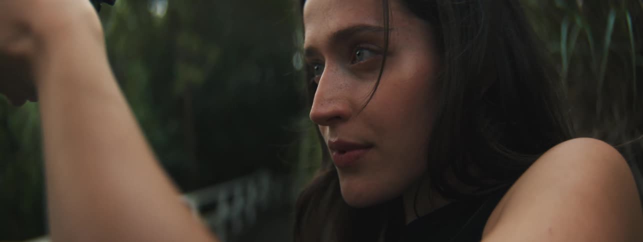 A woman with green eyes is holding a camera in her hands and is smiling