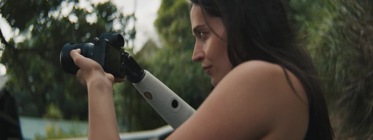 Female photographer holding her professional camera with one of her mechanical hands in an outdoor environment
