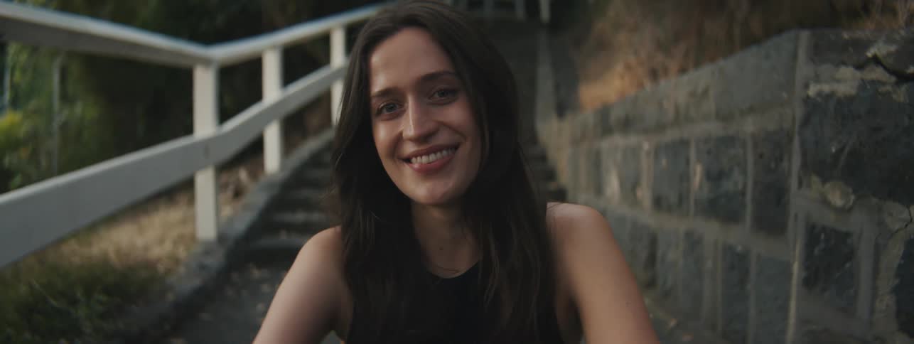 A woman smiles as she poses while sitting on some stairs outdoors