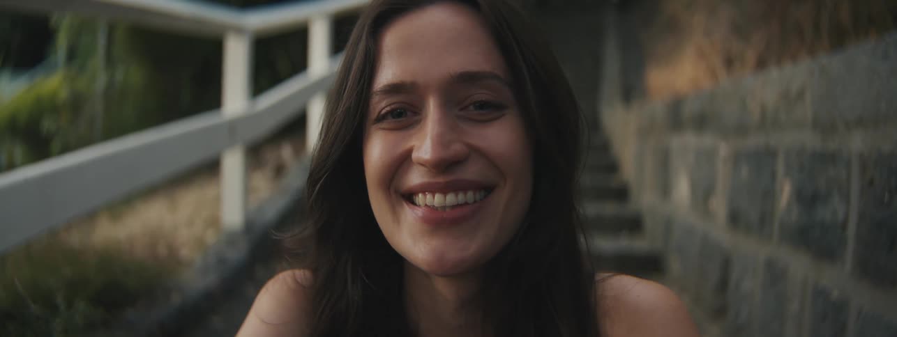 Face of a lady smiling while seated on the outdoor stairs at sunset