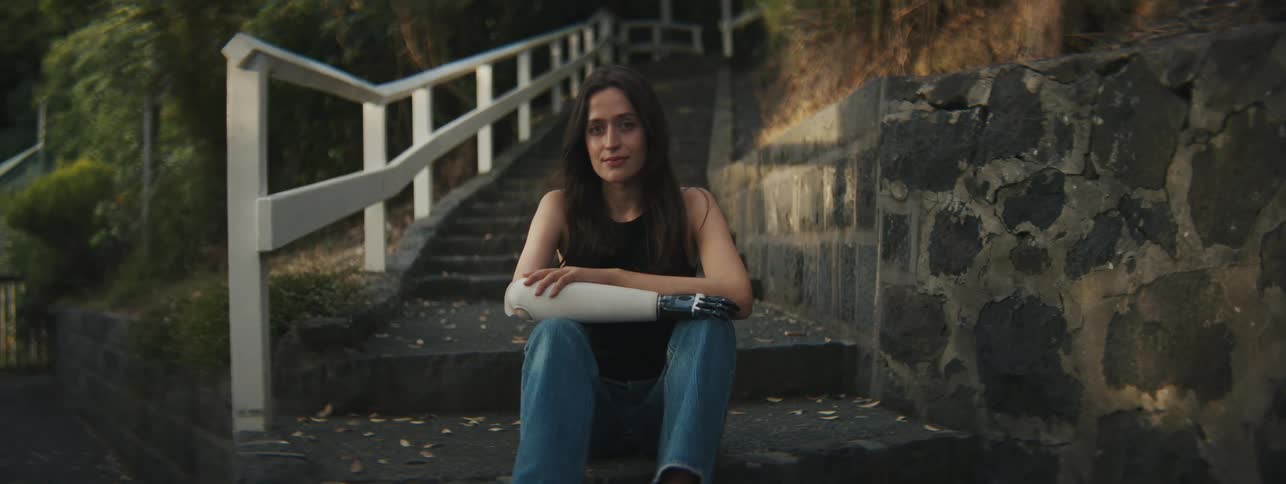 Woman sitting on steps outdoors surrounded by vegetation and trees