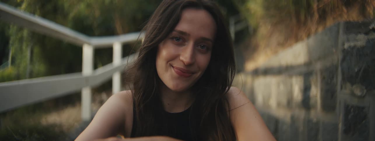 A woman sits outside and smiles