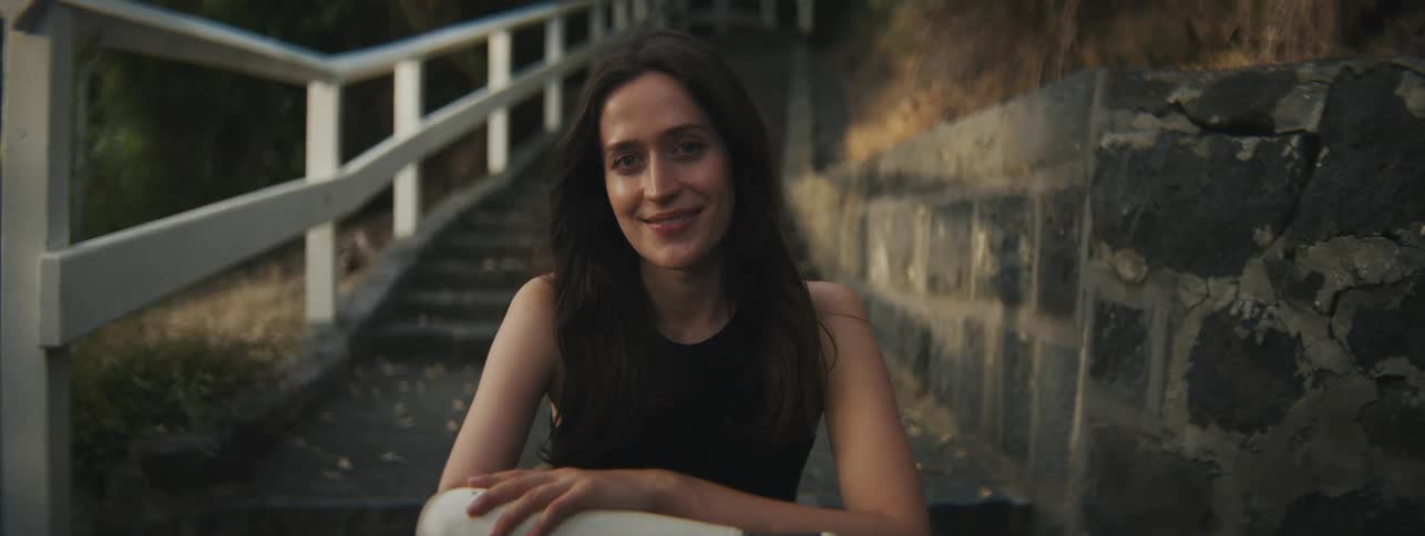 A female smiling while sitting on the stairs outdoor at night