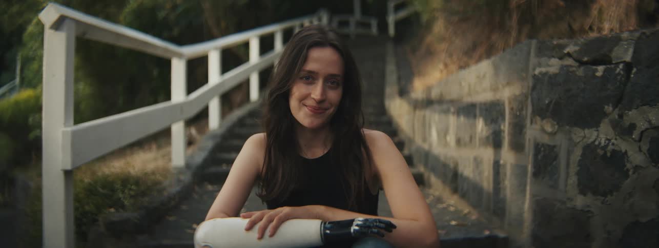 A woman with an artificial arm sits near stairs