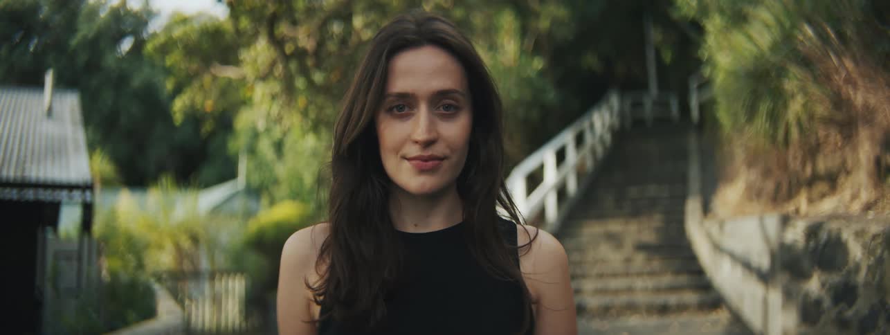 Face of a female standing outdoor near the stairs with little smiles