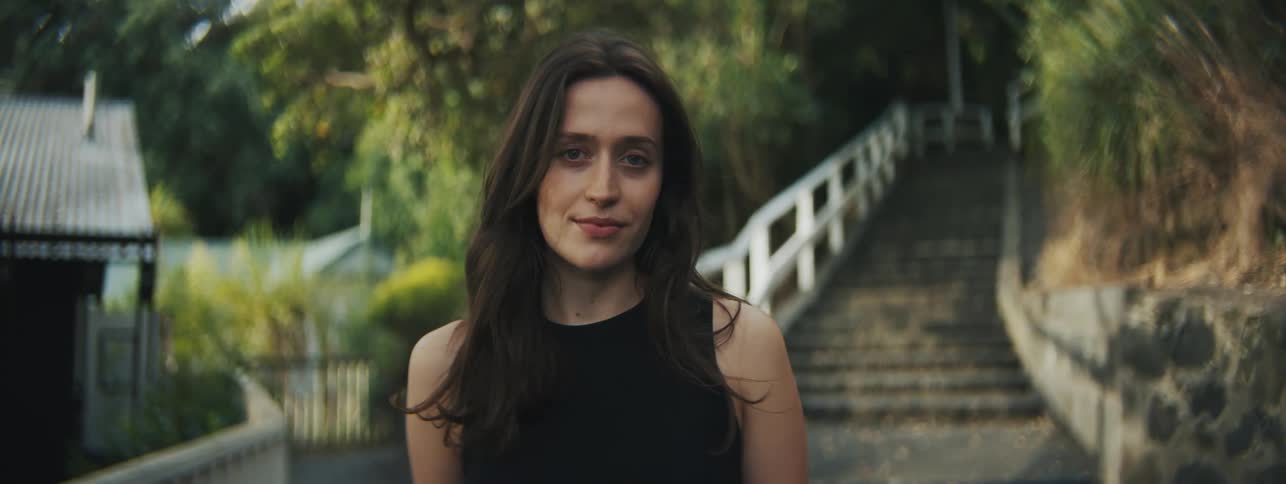 A woman smiling while standing in front of a stairwell leading to a park