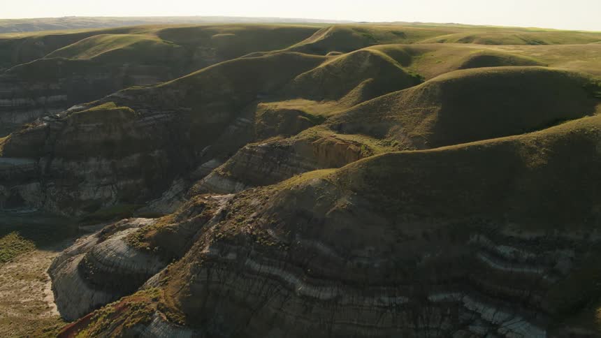 Badlands ridges, coulee and hills with grass and visible sedimentary rocks from above