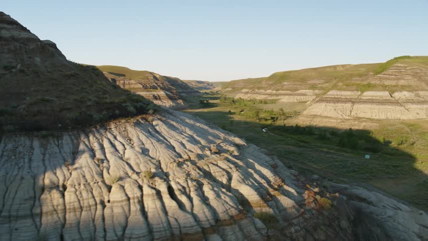An aerial view moving through a grassy coulee in the badlands