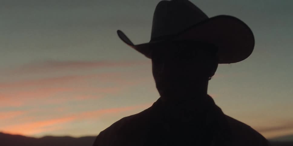 A man wearing a cowboy hat turns around