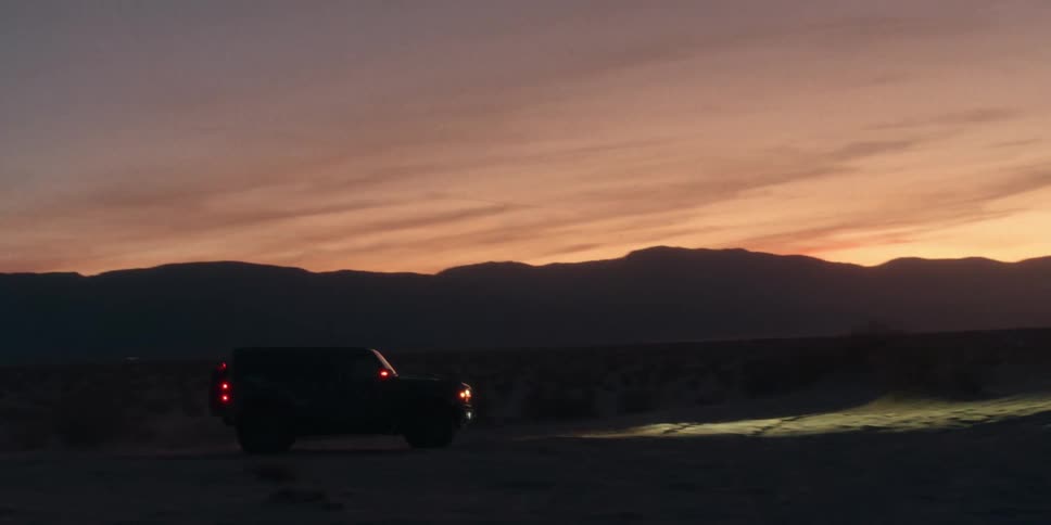 A vehicle drives across a grassy plain