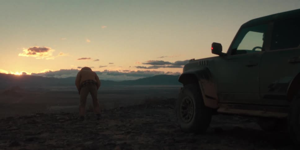 A man bends over near his vehicle