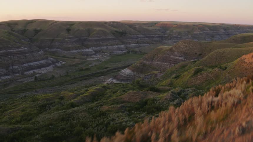 Flying over a grassy coulee in the badlands at dusk