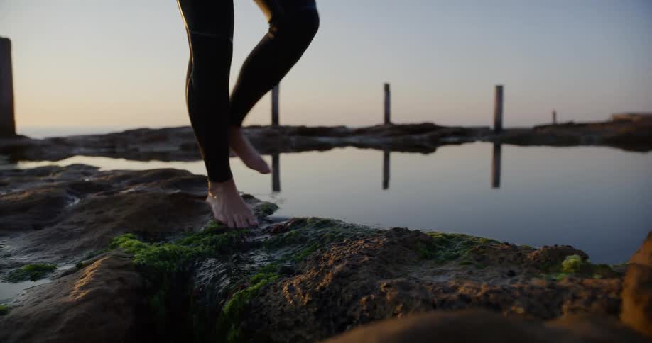 A person is walking on the stones by the shore