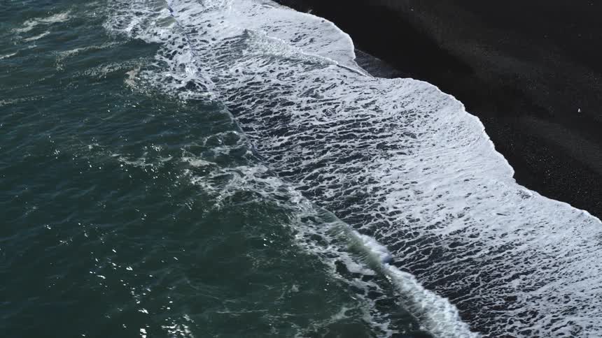 Foamy waves climb the sandy beach