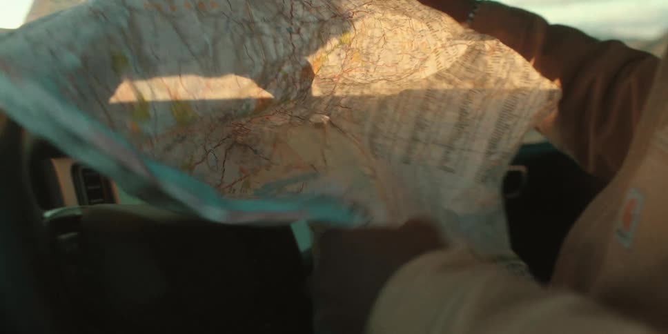 Hands of a man inside the car opening a map
