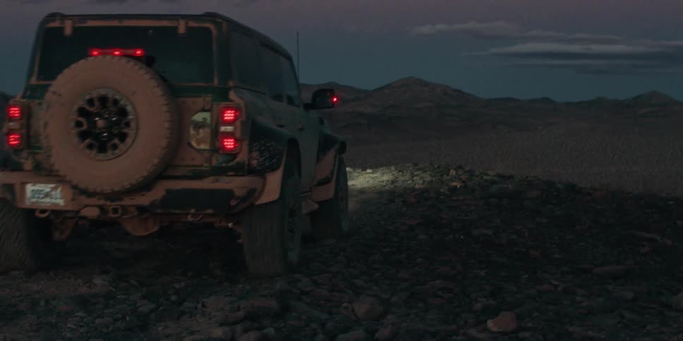 Jeep drives over rocks in the desert toward the mountains