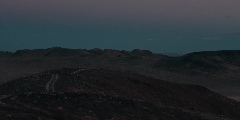 A car drives down the road over the hills