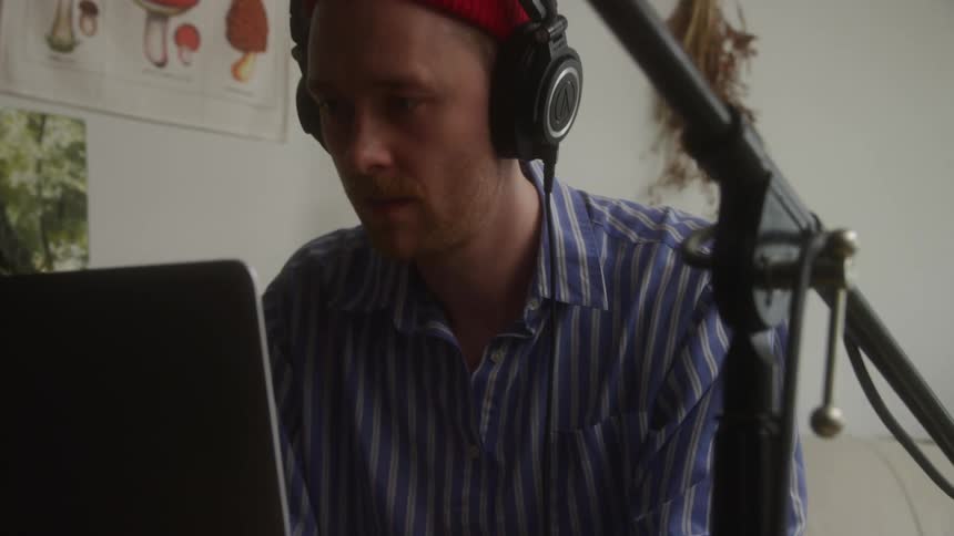 Portrait of a concentrated man with headphones in front of his laptop