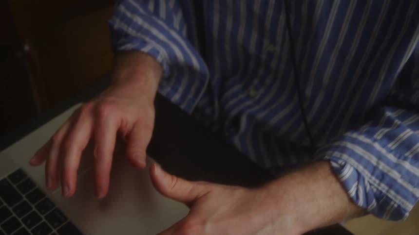 Man sitting at a desk and typing on a laptop