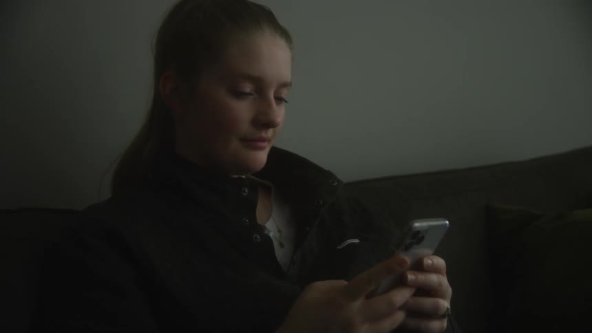 Woman sitting on a sofa taking out her smartphone and typing