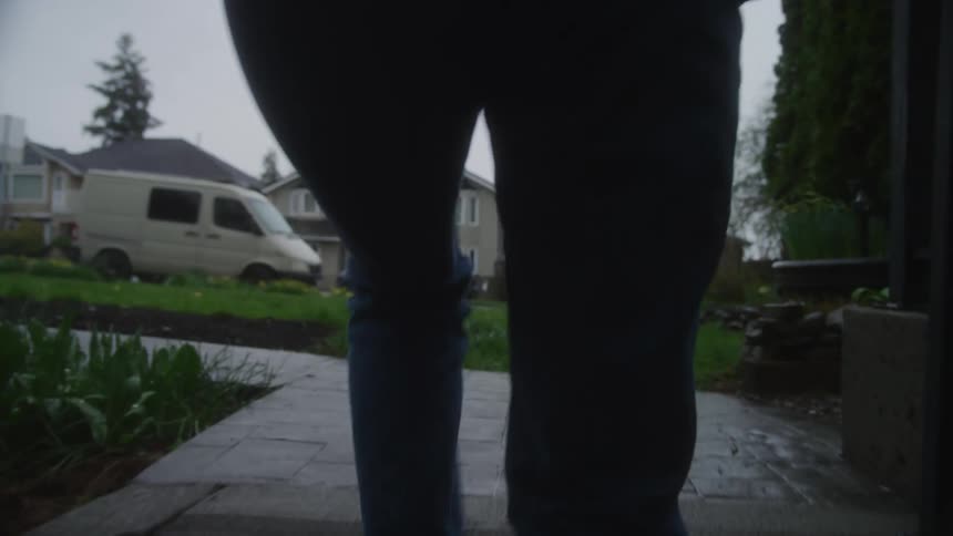 Woman wearing a jacket and climbing a ladder outside her home on a cloudy day