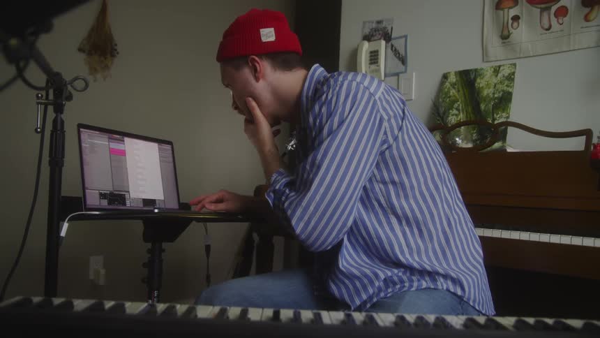 A musician fiddles with a laptop