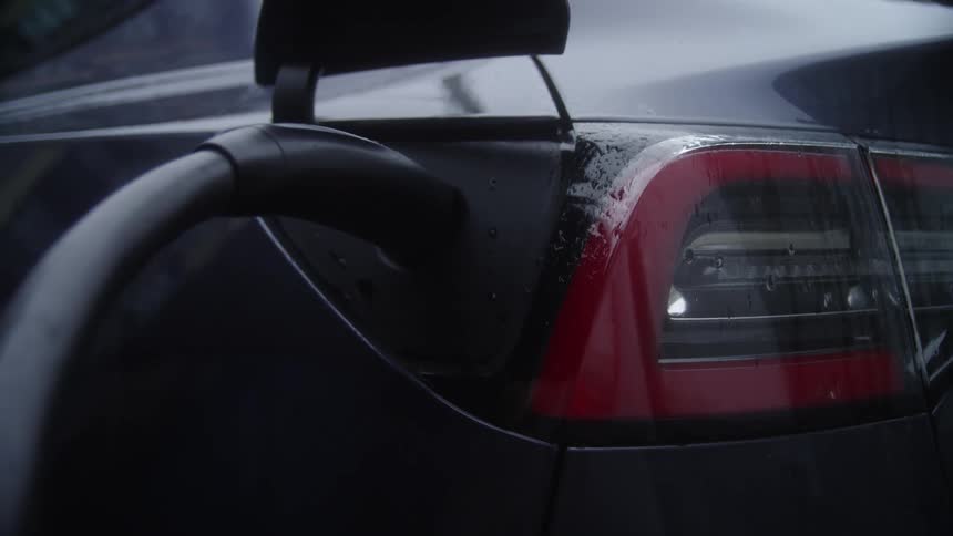 A persons hand opening the car socket to charge electricity