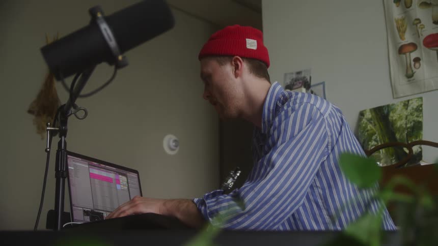 A musician works on a laptop while bobbing his head