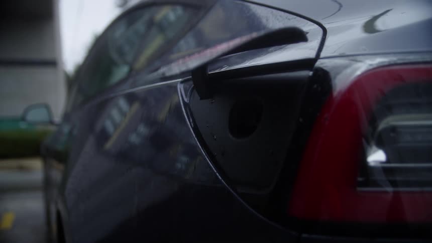 A woman gets out of her car to charge