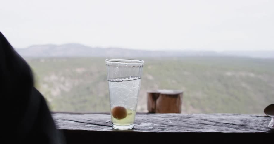 A man breaks an egg and drops it into a glass filled with liquid