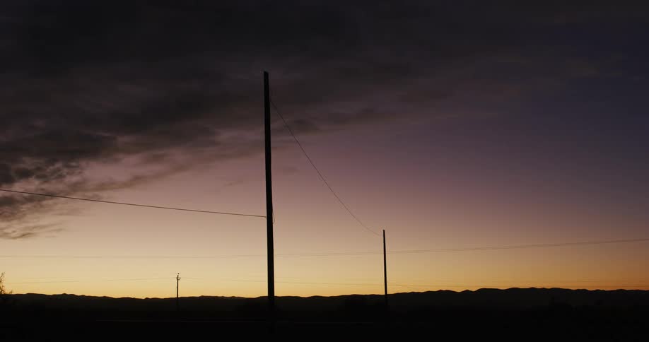 Power lines tower above the low ground at sunset