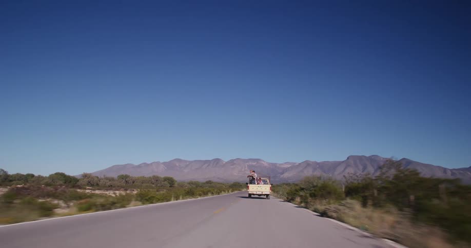 A pickup truck is driving down the desert road