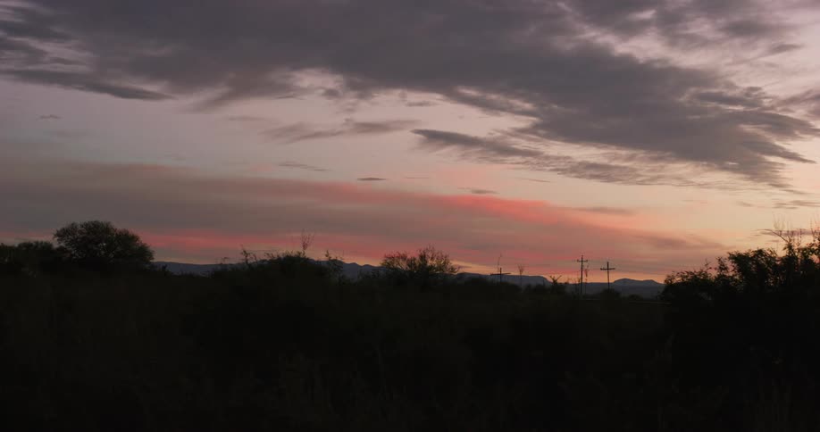 Silhouette of a forest with mountains on the horizon on a reddish morning sky