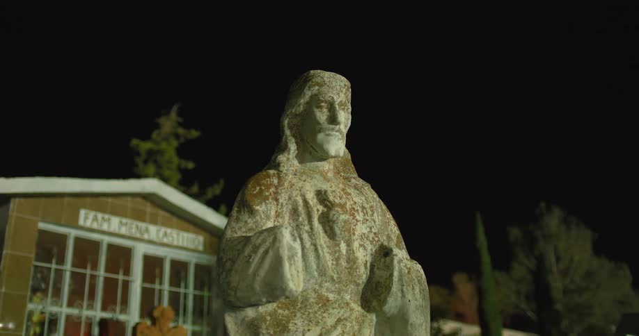 Mosscovered statue in front of a brown tiled building at night