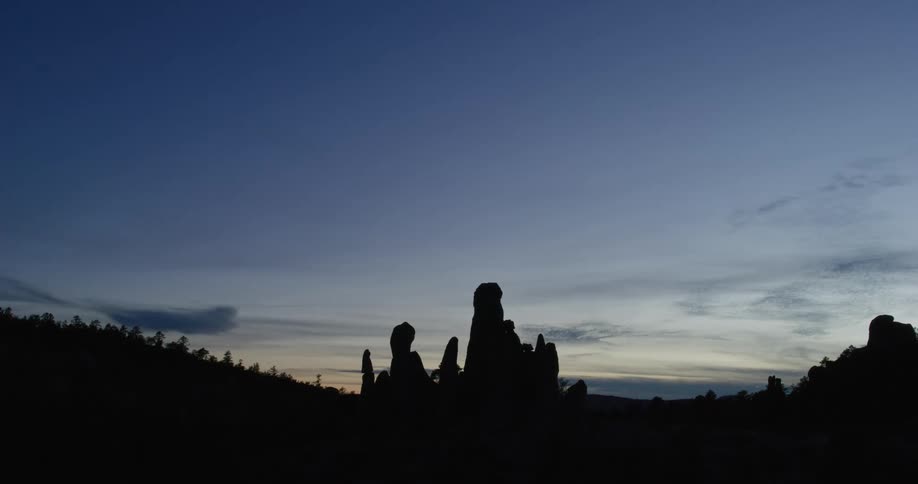 Silhouettes of tall rock formations against a colorful sunset sky