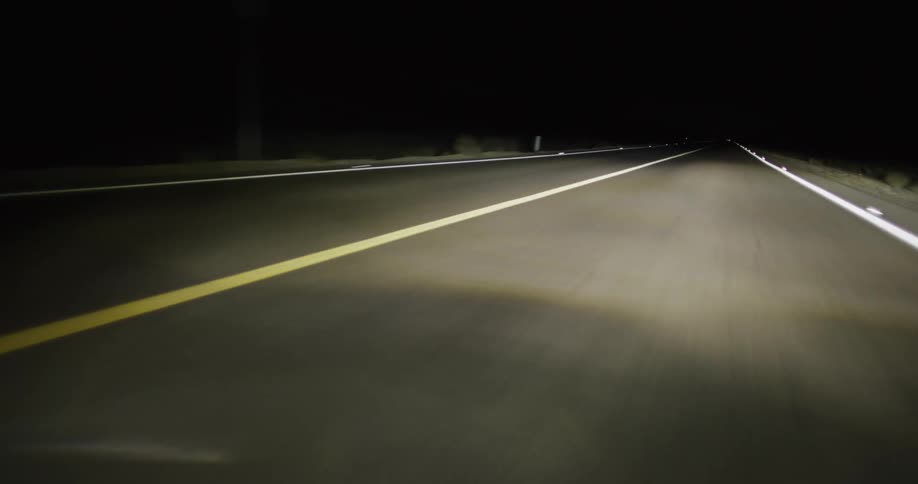 Automotive headlight moving on a road at night