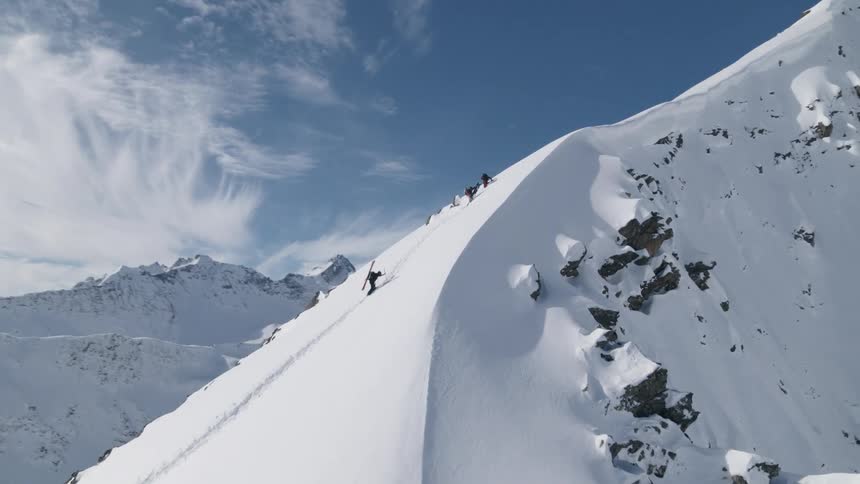 People are climbing up the mountain with their skis