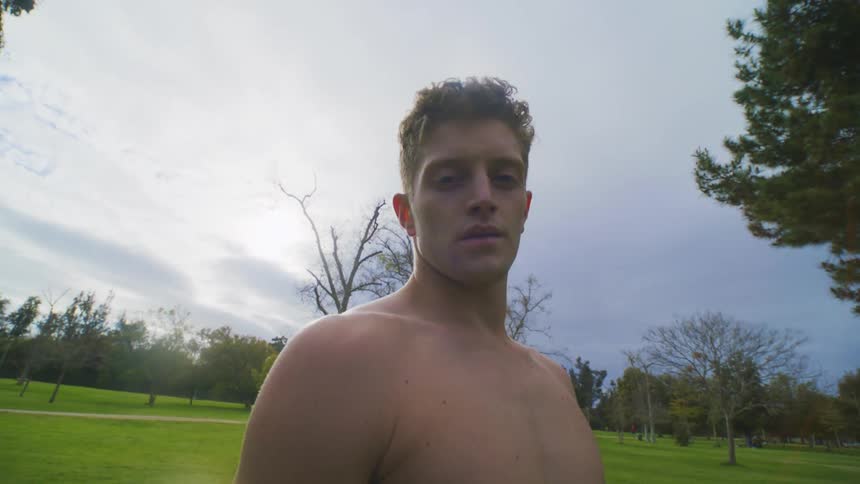 Close up of a shirtless muscular man on a park at morning