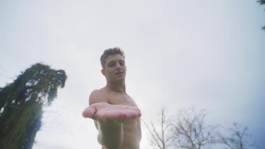 A young white man engages in involved stretching outdoors