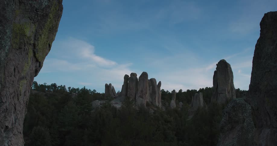 Narrow tall rock formations loom over a forested area
