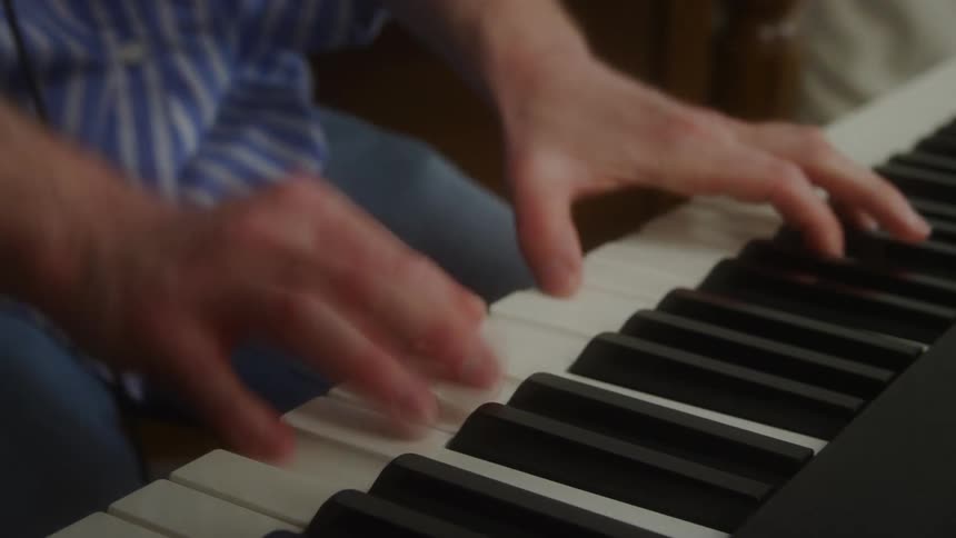 Person sitting down and playing the piano instrument