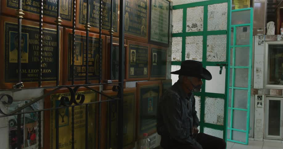 A man with a cowboy hat and a headset sits in a room