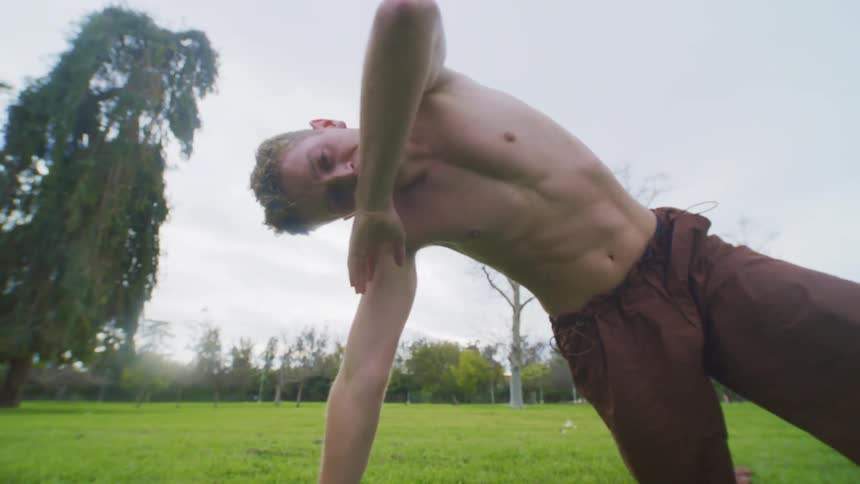 A topless man stretches on a grassland