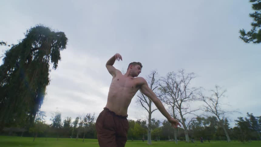Man performing a type of dance by himself on a lawn of grass