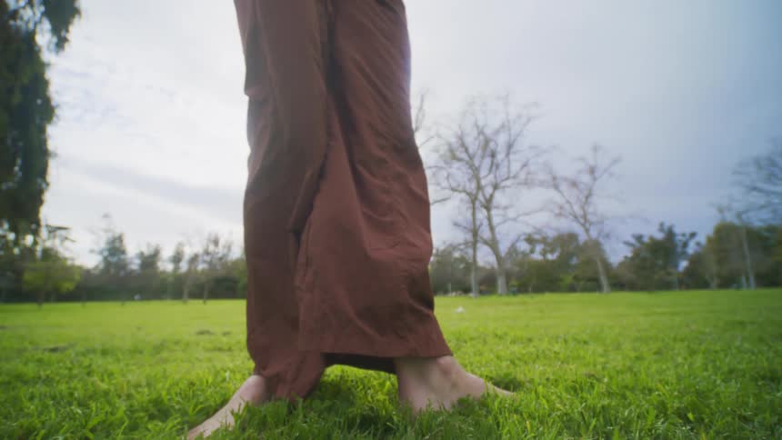 A woman is dancing outdoors barefoot on the green grass